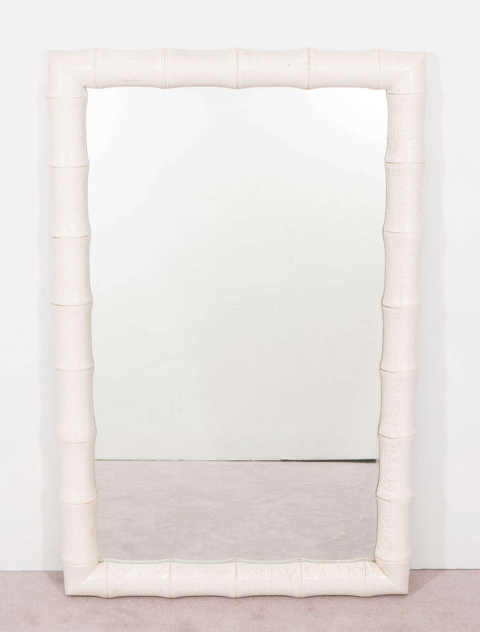 A vintage wall mirror, produced, circa 1970s, inset within a stylistic bamboo frame and veneered in faux white snakeskin, inspired by the designer Karl Springer. Very good vintage condition, with minor scratches and chips to the surface of the frame.