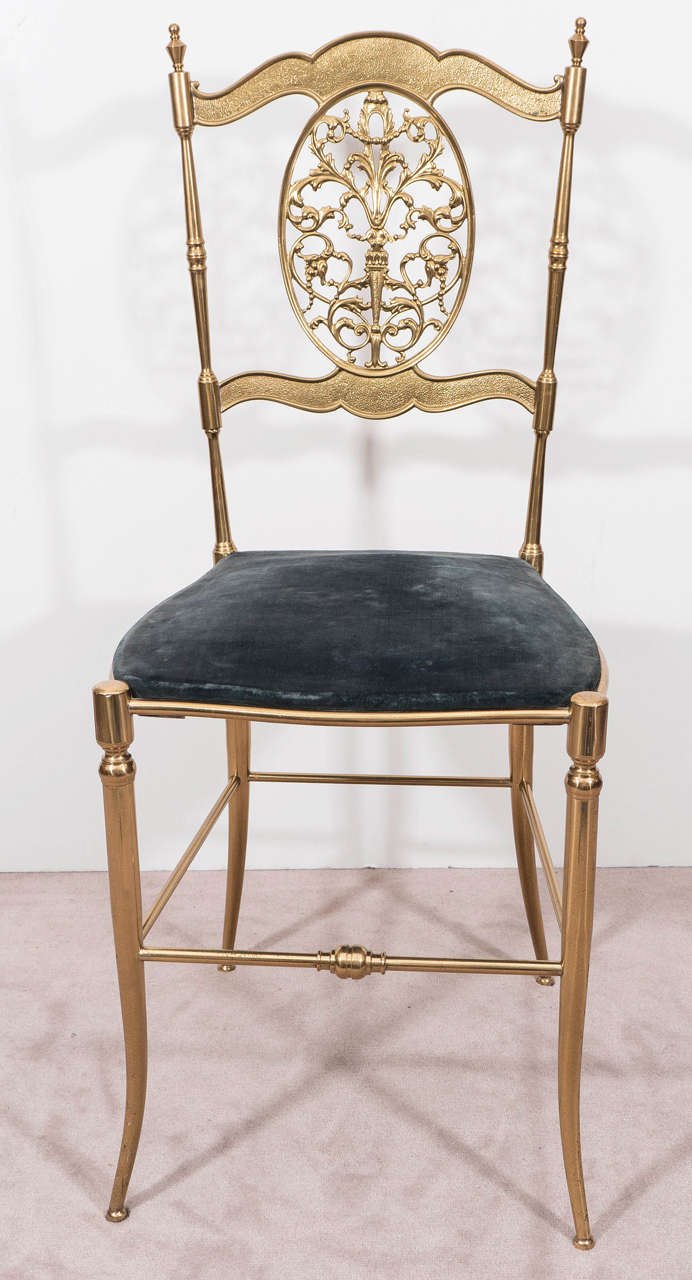 A vintage Chiavari chair, produced in Italy, circa 1950s, with brass frame in the neoclassical style and oval back splat with arabesque scroll work, over a blue velvet seat. Very good vintage condition, with some age appropriate wear, minor