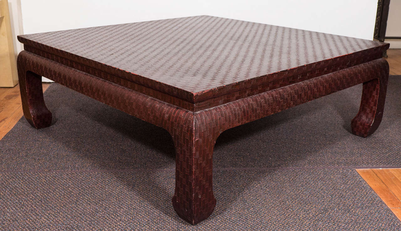 A vintage coffee table, in the style of Karl Springer, produced between 1960s-1970s by Baker Furniture Company, entirely in grasscloth, lacquered in a deep burgundy red, designed within the chinoiserie mode. Markings include Baker Furniture label,
