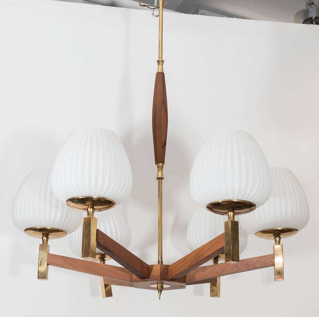 A Scandinavian six-arm chandelier, in the Danish style, with suspending rod and decorative accents in polished brass, each arm supporting a ridged tulip-form globe in milk glass. Very good condition, consistent with age and use.