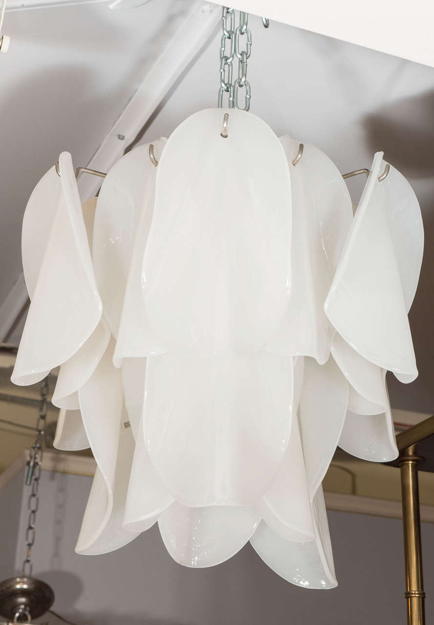 A vintage Italian chandelier, produced circa 1970s by Mazzega, with petal shaped, white 'opaline' Murano glass shades, suspended in layers to a metal frame. Wiring and sockets to US standard, requires four candelabra base bulbs (25-30 watt