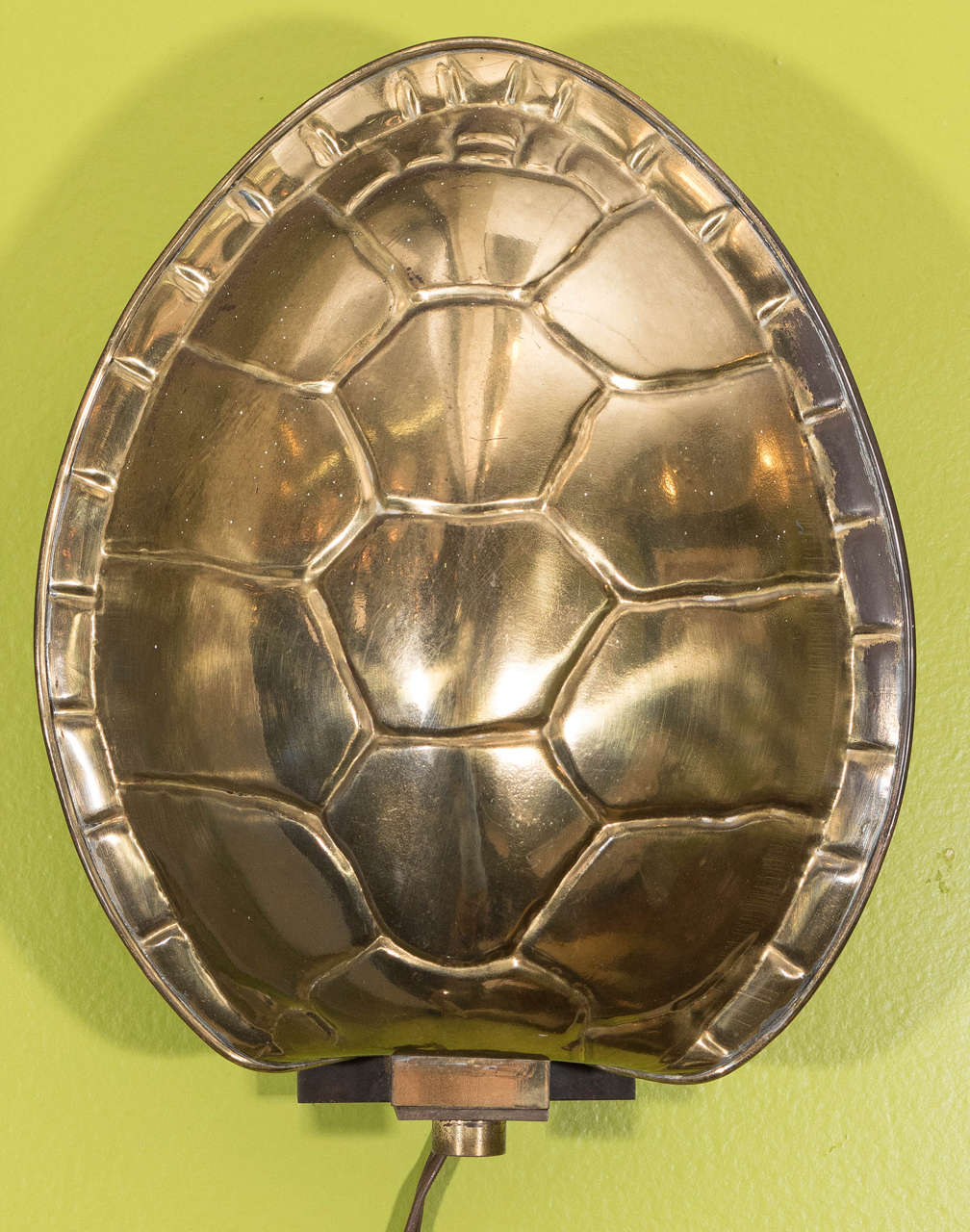 A vintage sconce, with polished brass shade in the form of a tortoise (or turtle) shell, produced between 1970 and 1980 by Chapman Manufacturing Company. Requires one Edison base bulb. Very good condition, with age appropriate wear and patina.