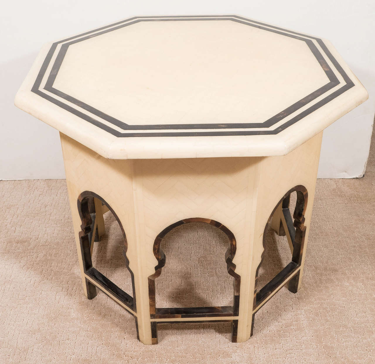 A modernistic approach to a Moorish inspired end or side table, with octagonal top and base, each side with cutouts of Moroccan arches and spreaders, veneered in tessellated bone, with tortoise shell accents. Good condition, consistent with age and