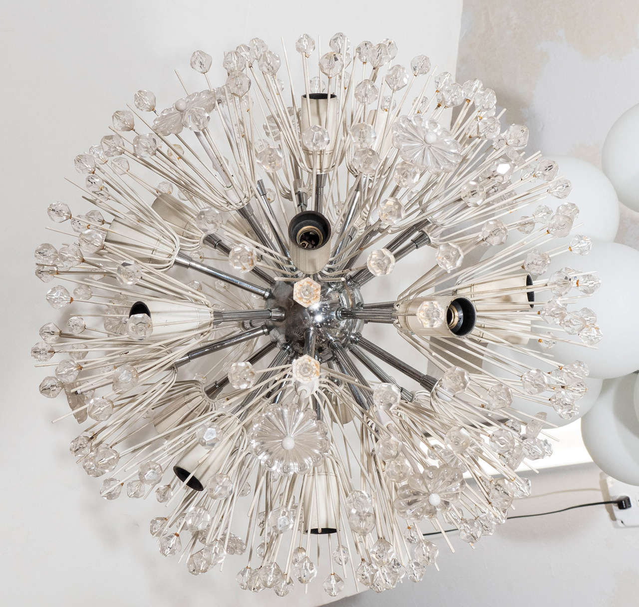 A vintage sputnik chandelier, produced mid-century by Austrian designer Emil Stejnar, with chrome frame and central nucleus, and white enamel sockets and spokes, decorated with acrylic florets and faceted beads. Requires candelabra base bulbs. Very