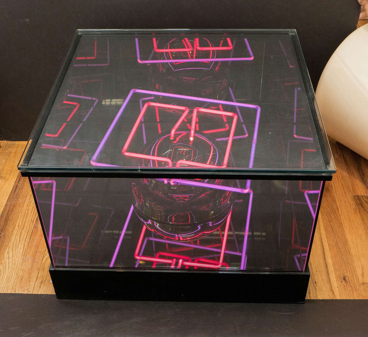 A vintage light box and decorative end table, produced circa 1970s, in glass and Lucite, with pink and violet neon lights affixed to a sphere nucleus; against the reflective interior, the lights appear as multiple-dimensional patterns. Good vintage