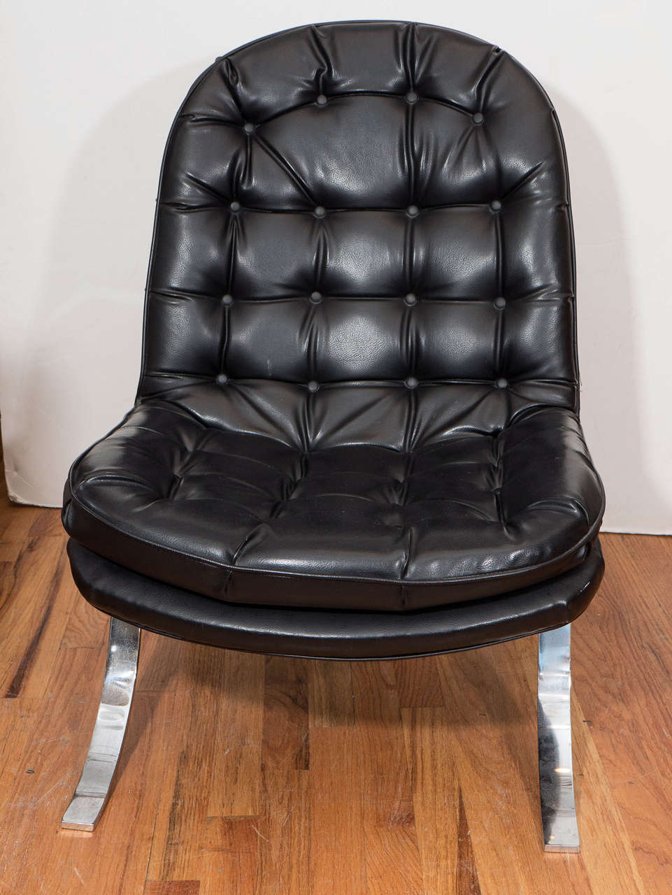 A vintage lounge chair, in the style of Swedish designer Arne Norell's 'Ari' chairs, produced circa 1960s-1970s, upholstered in tufted black vinyl on flat, chrome Klismos form legs. Good vintage condition, with age appropriate wear and minor patina