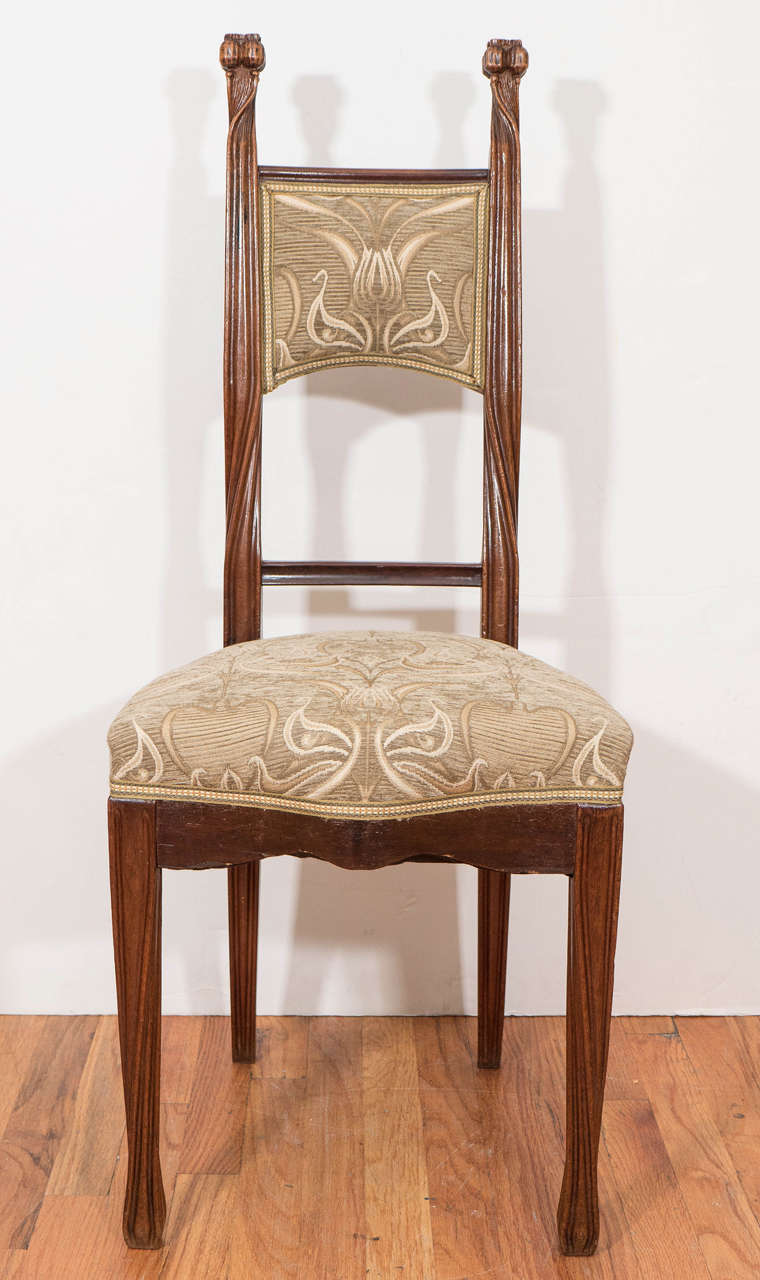 An antique French Art Nouveau chair, designed and manufactured by Louis Majorelle, circa 1890-1910, in beautifully detailed hand-carved wood frame, with twisted uprights, terminating in stylized poppy seed finials, the cushioned back splat and seat