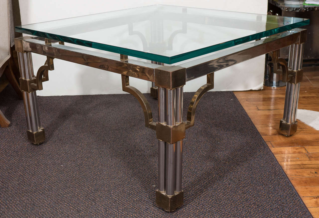 A vintage coffee table, produced circa 1980s, with raised glass top on chrome frame, following a stylistically Asian motif, above tri-column legs, accented with squared brass knuckles. Good vintage condition, with age appropriate wear, including