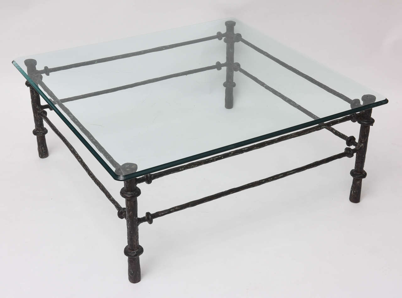 Patinated-bronze finished coffee table in the manner of Diego Giacometti. Half-inch glass top.