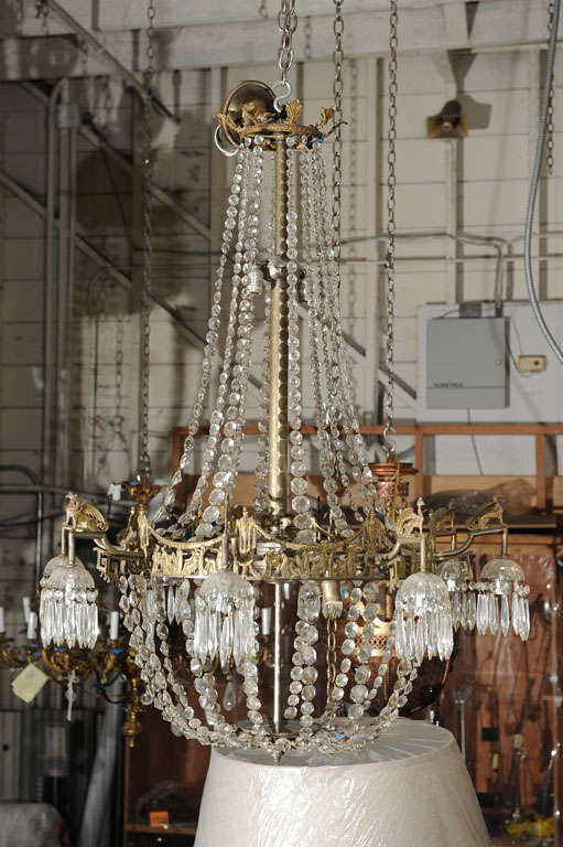 Grand 16 light chandelier in the neoclassical style.  Frieze of toga clad figures with garlanded urns, crystal drops surrounded downlights with griffin supports; acanthus leaf upper crown.  Newly rewired.