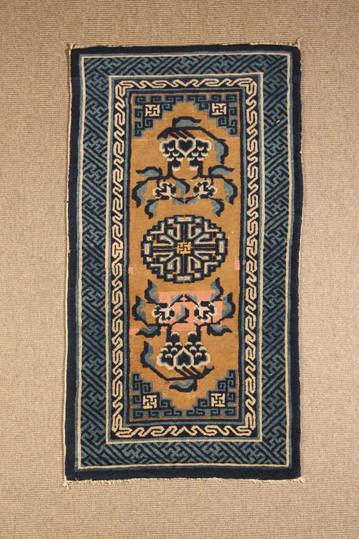 A fine Chinese Paotow carpet. Of rectangular form, the carpet woven with centered stylized shou (long life) ideography flanked by peony sprays with archaic dragon design corners, all against a light brown ground.  An inner border of chain link
