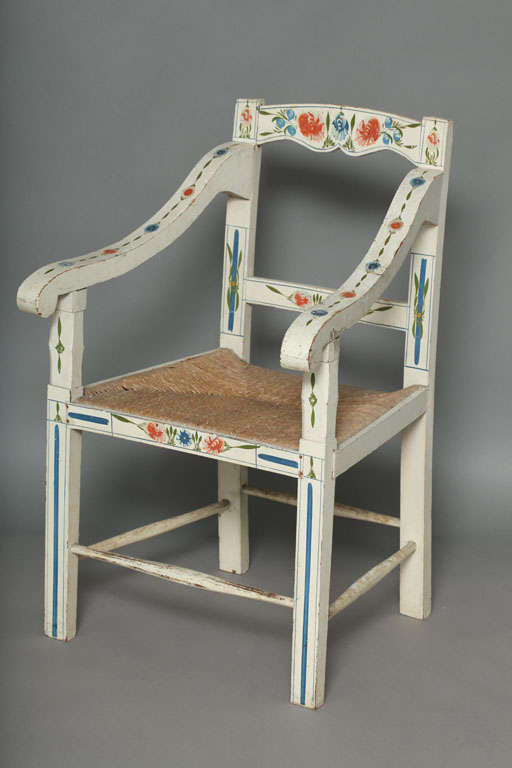 Unusual Scandinavian folk art armchair of simple form, the shaped backrest with downward shaped arms, over rush seat, the square legs joined by turned stretchers, the whole painted with flower head and leaf decoration on a pale blue/white ground,