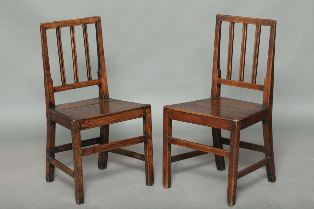 Good pair of early 19th Century English oak side chairs, the square backs with ribbed vertical slats over plank seats, the square legs joined by bar stretchers, both possessing rich color and patination.