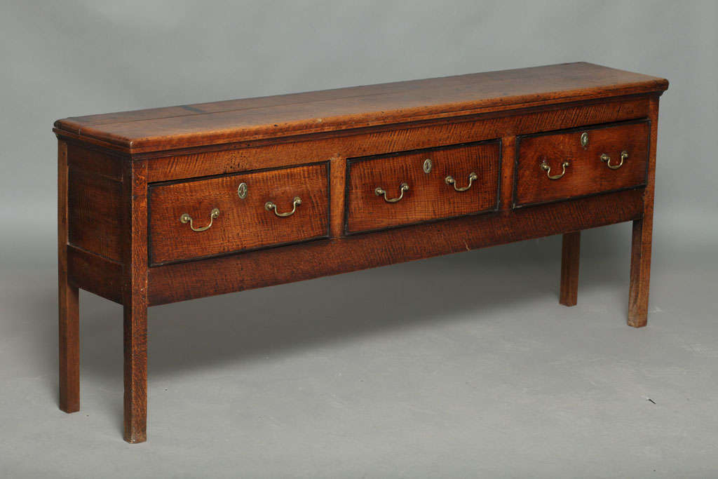 Very fine and extremely useful George III tiger oak low dresser of exceptionally narrow depth, the whole with vivid tiger striping, the top with rounded edges over three bog oak banded drawers having original brasses, standing on square legs, good
