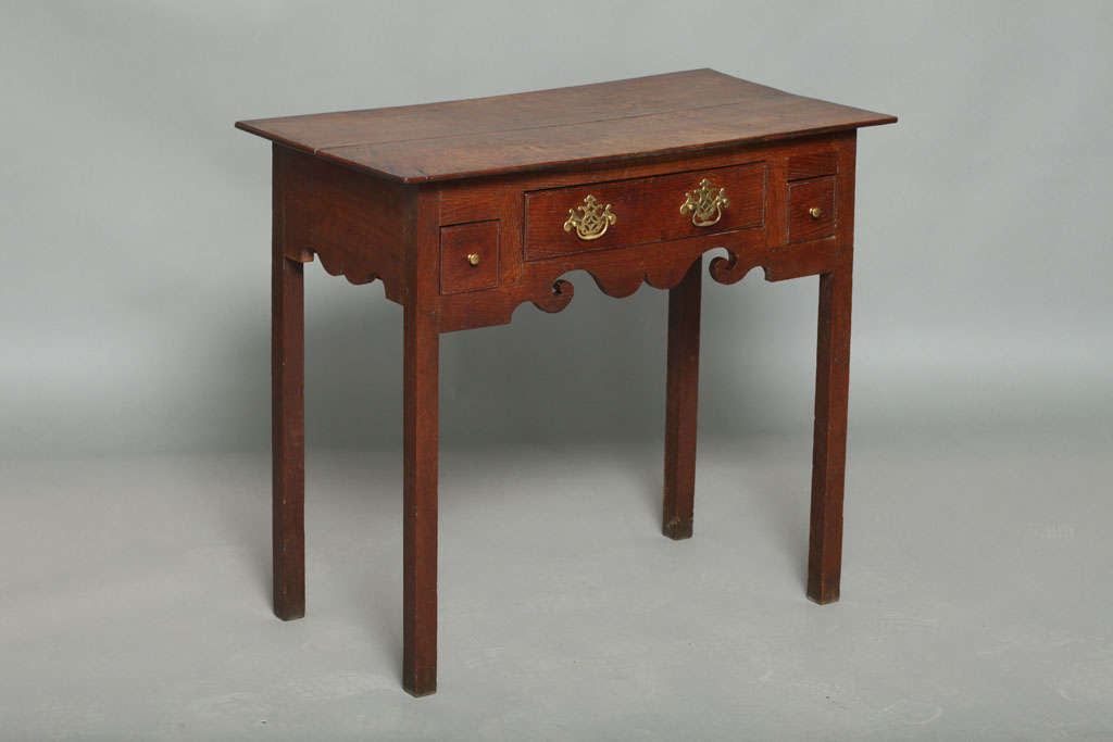 Fine 18th Century Welsh oak lowboy or side table, the two plank top over one long and two square drawers having original brasses, over richly scalloped apron, sanding on square legs, the whole with good rich color and graphic form.