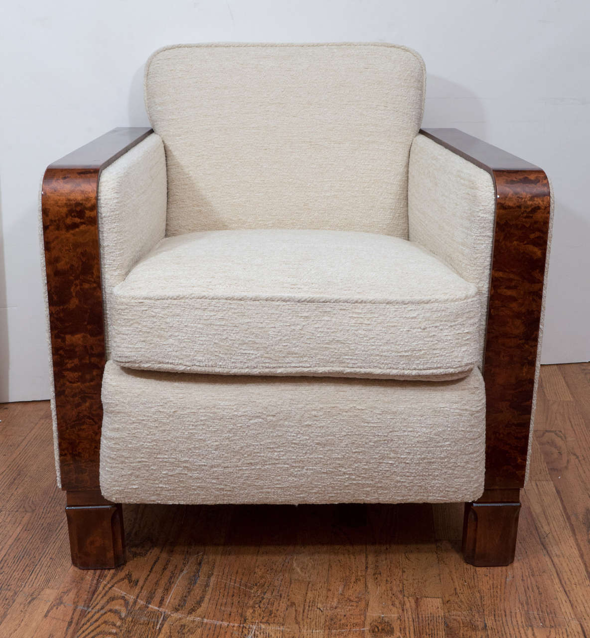 Solid, deep and extremely comfortable, these Art Deco club chairs illustrate the design influence of Cubism of the time. The plush, wool bouchle upholstery adds a creamy texture while the elegant, yet fiery, walnut stained arms and legs hug the
