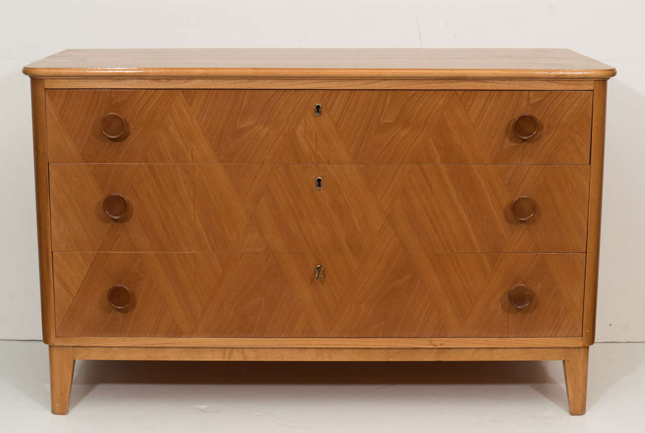A locking ash chest with harlequin-patterned ash parquetry adorning the three drawers, with original solid ash pulls. The deep drawers slide open easily and are constructed of solid wood; this means they will never warp. Perfect for extra storage,