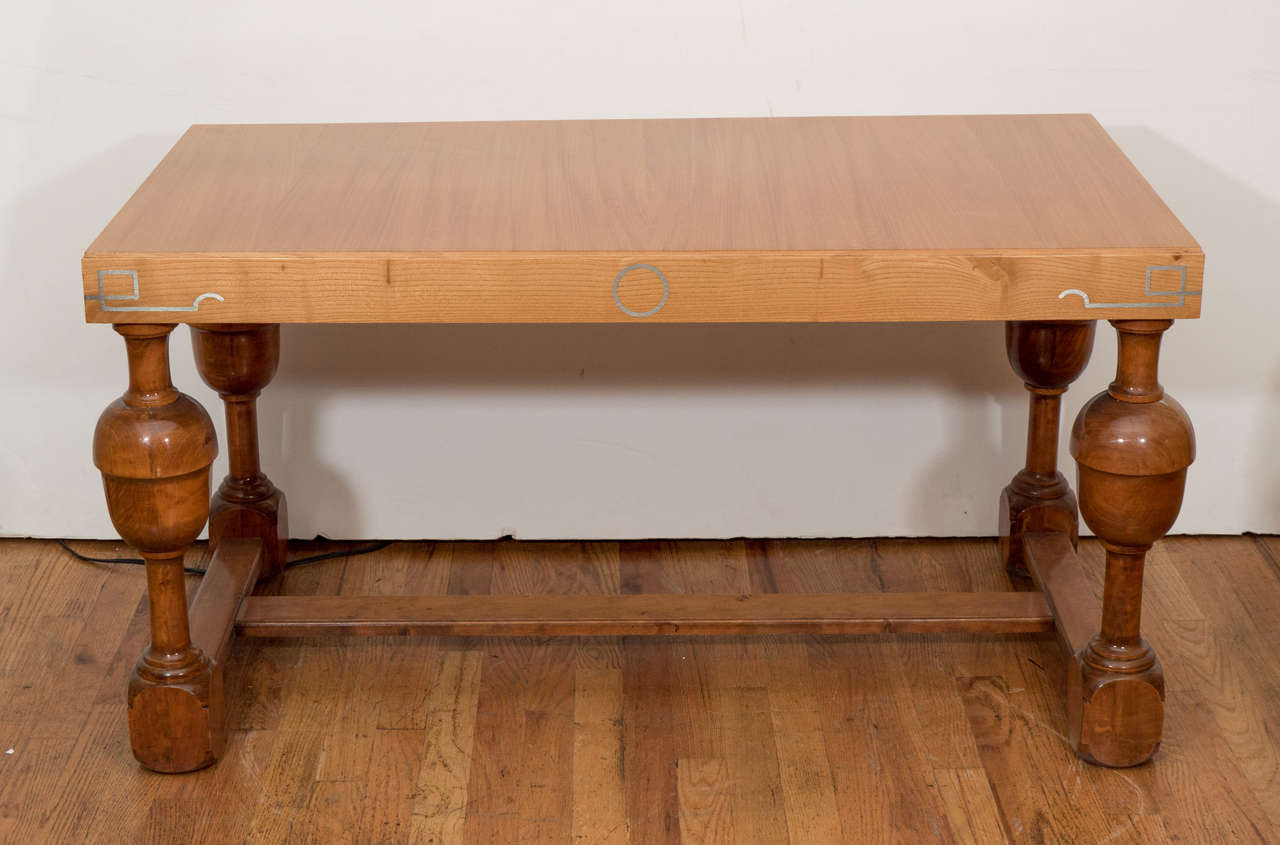 Dieser ebenso schöne wie robuste Tisch aus Esche und Birke zeichnet sich durch stilisierte Messingintarsien rund um die Schürze aus.