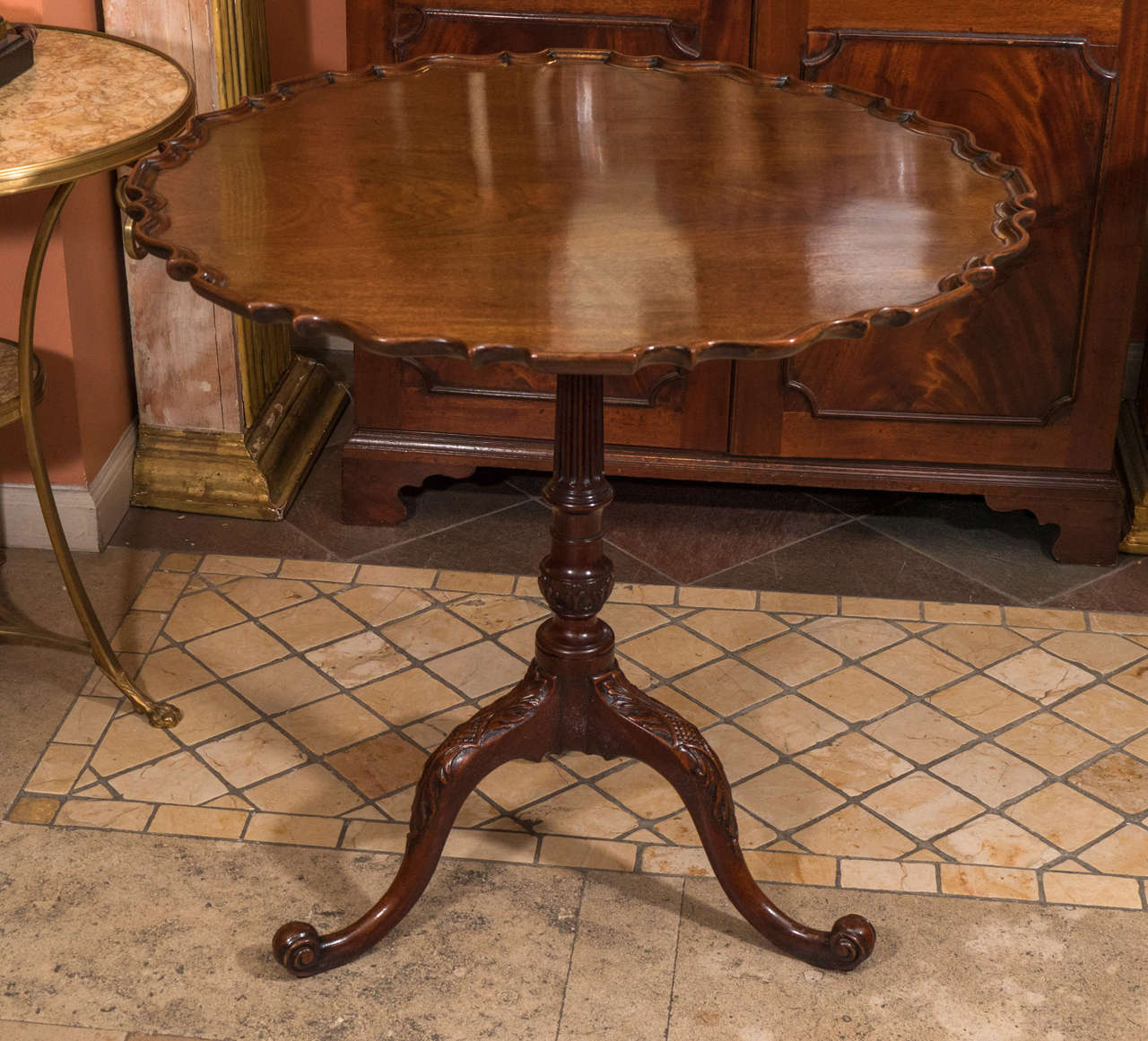 A large George II mahogany carved tilt top pie crust table with fluted shaft and scroll feet.