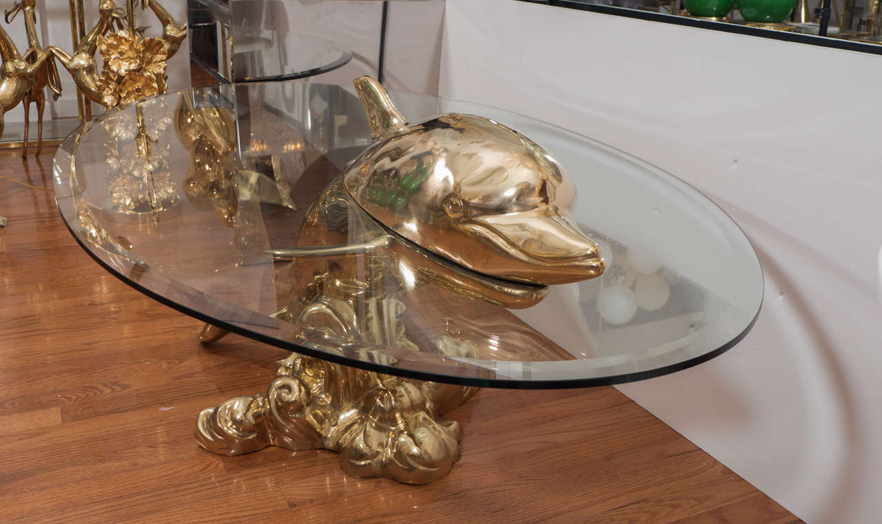 Sculptural brass coffee table with dolphin form base.