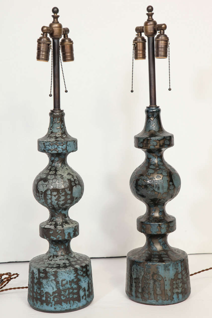 Baluster form bodies in redware glaze with mottled blue-grey matte volcanic glaze under a network of hematite black metallic drip glaze, German, circa 1960, newly rewired for US usage. Lamp bodies 21.5 inches high.