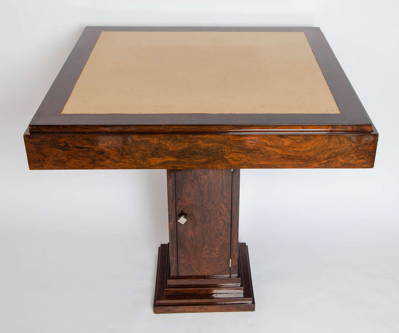 An Art Deco games table designed by Pierre Gouffé of the Maison Gouffé of Paris. Rosewood, with reverse panel top with baize panel to underside, over a walnut and ebony inlaid backgammon table. Set on a square pedestal with integral, shelved