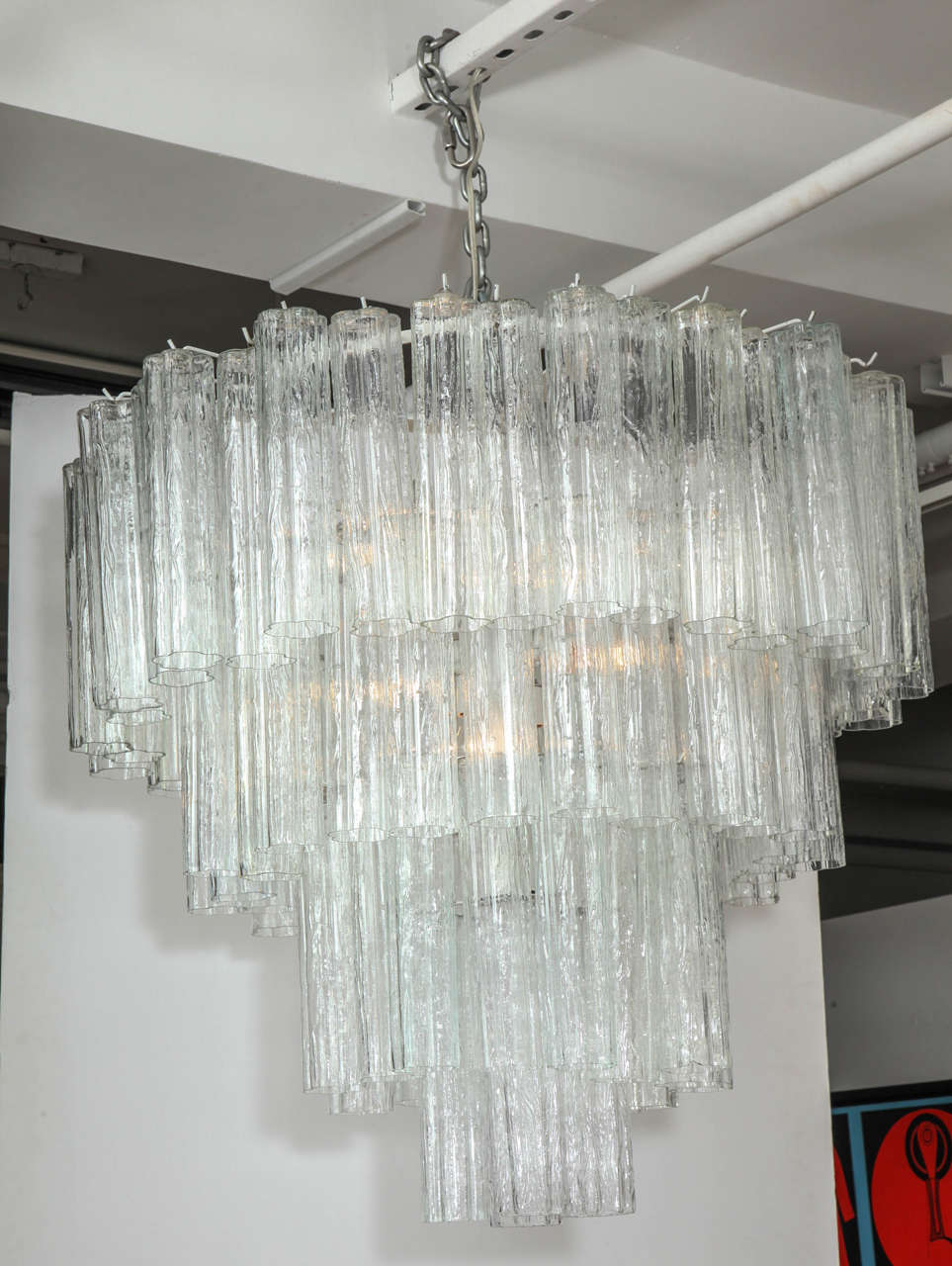 Timeless Italian classic  tronchi tube chandelier by Venini, retailed thru Camer Glass NYC. Four tiers of glass tubes are suspended from a painted white frame. Up to three feet of brass chain and canopy included. Uses eight Edison type bulbs.