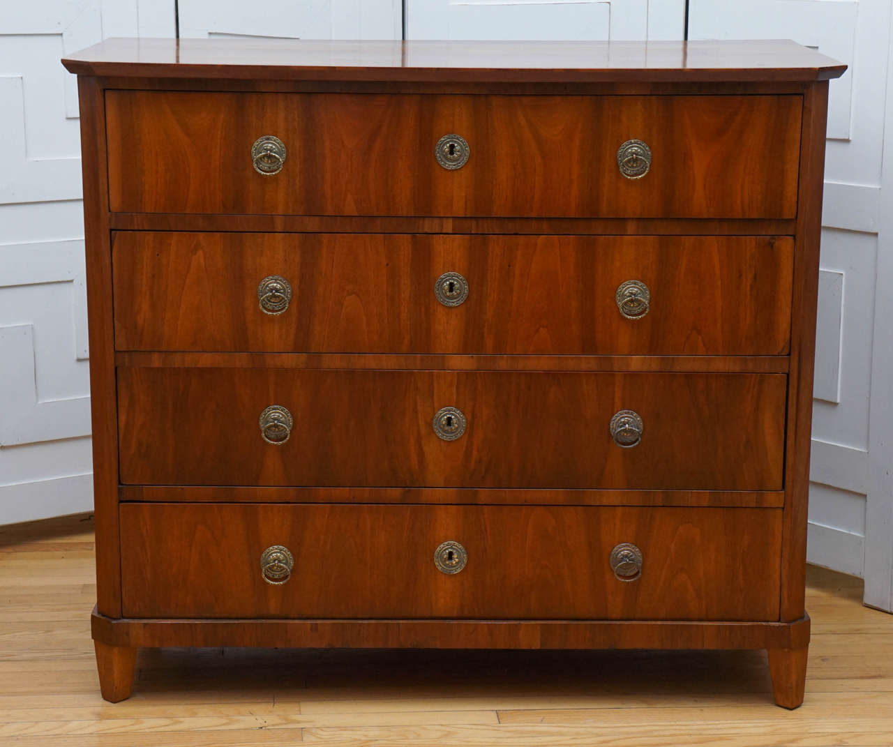 Walnut continental chest with four drawers and brass details.