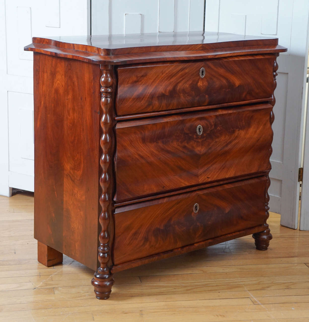 Biedermeier chest of drawers with carved details and flame mahogany drawer fronts.