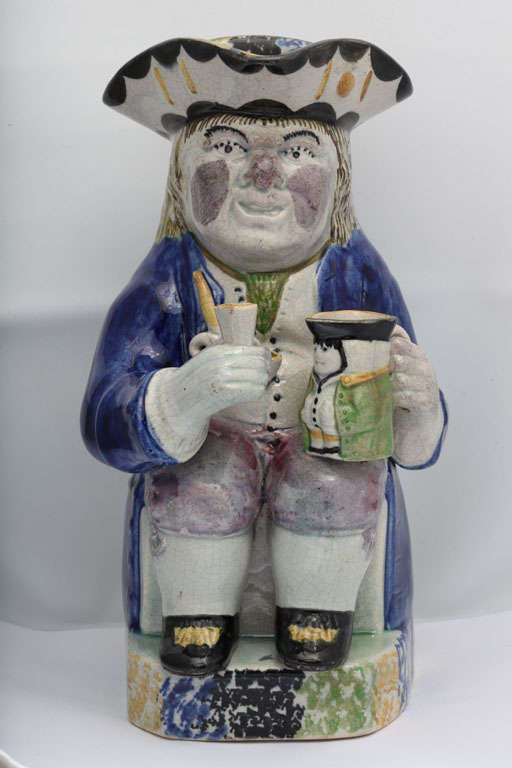 A  fine English pearlware toby jug holding a second toby and beaker, coiled pipe on vest and figural handle, deocrated in underglaze Pratt colors