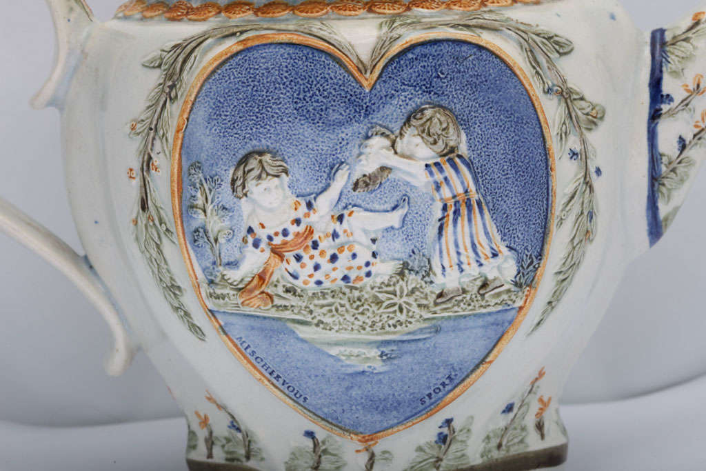A rare English pearlware teapot with Sportive Innocence and Mischievous Sport within heart shape panels, decorated in underglaze Pratt colors