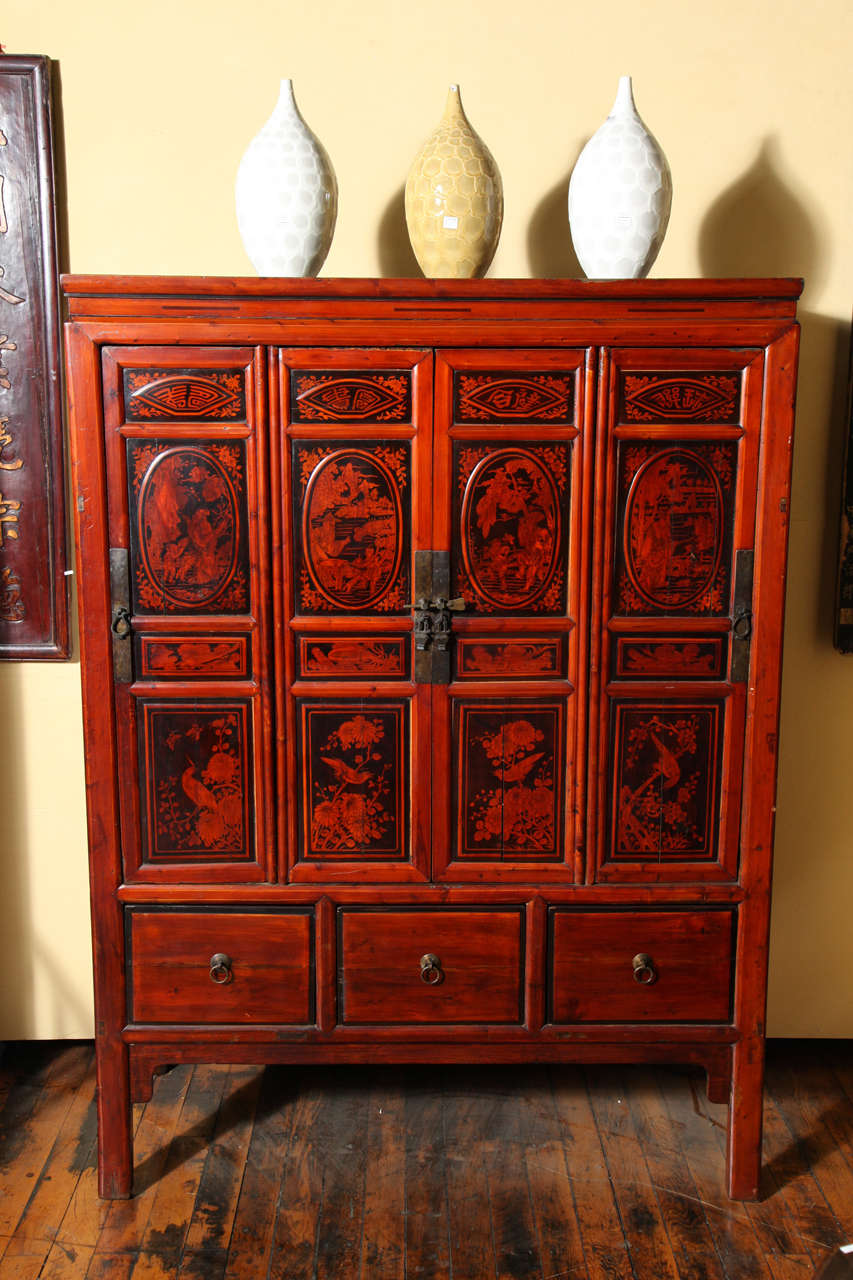 This Chinese large late 19th-early 20th century cabinet features four doors adorned with lacquered floral motifs over three drawers. The four unusual doors open up to reveal various inner shelves and drawers. The upper section of the recessed door