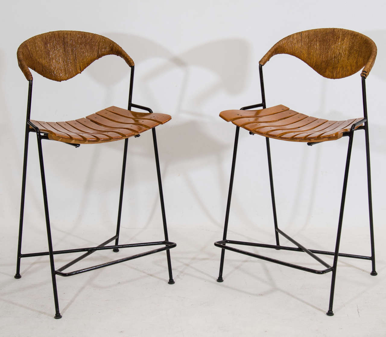 Striking pair of classic Arthur Umanoff bar stools with fixed slatted bent wood seats and sculptural grass back rests. This pair is counter height; we also have a pair, same design, that are standard height stools. Located at ABC Home, 646-602-3519.