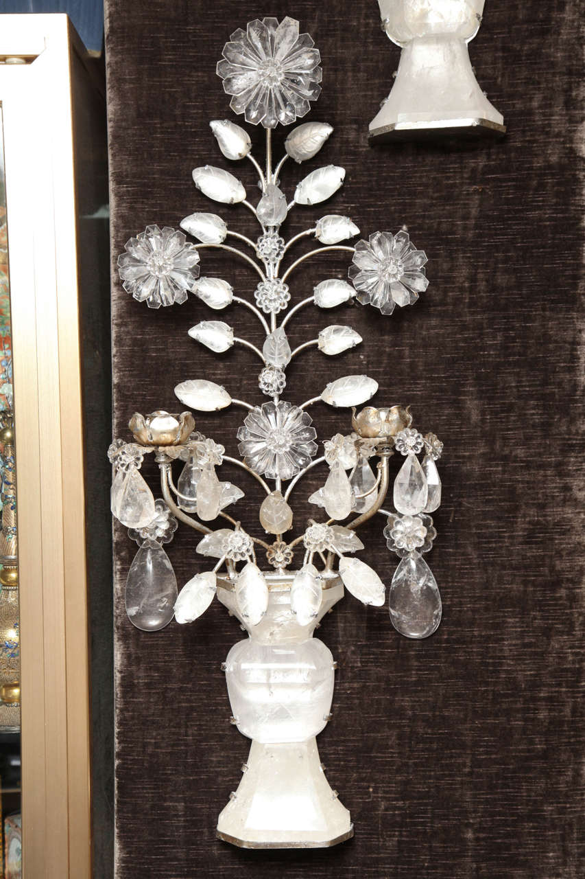 A pair of double-light rock crystal quartz and silvered bronze scones or wall appliqués in the style of Baguese, Paris. These exquisite hand cut and hand-polished rock crystal scones mimic the image of a vase filled with flowers. The crystal glows