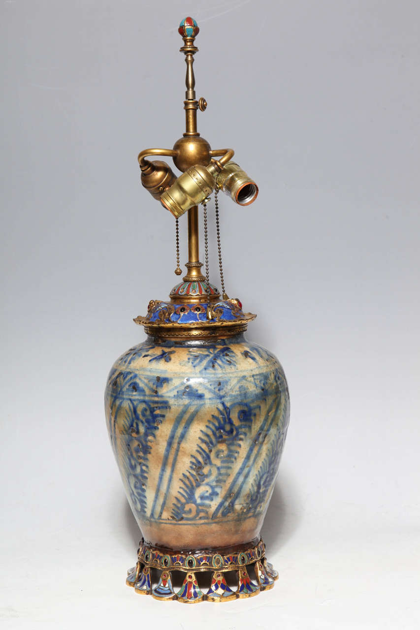 A Chinese/Korean porcelain, ormolu, enamel and jewel mounted lamp by E. F. Caldwell.  Finely mounted with figures of Phoenix's and geometric enameled objects. The cream and blue porcelain is hand painted with bands of repeating motifs. The