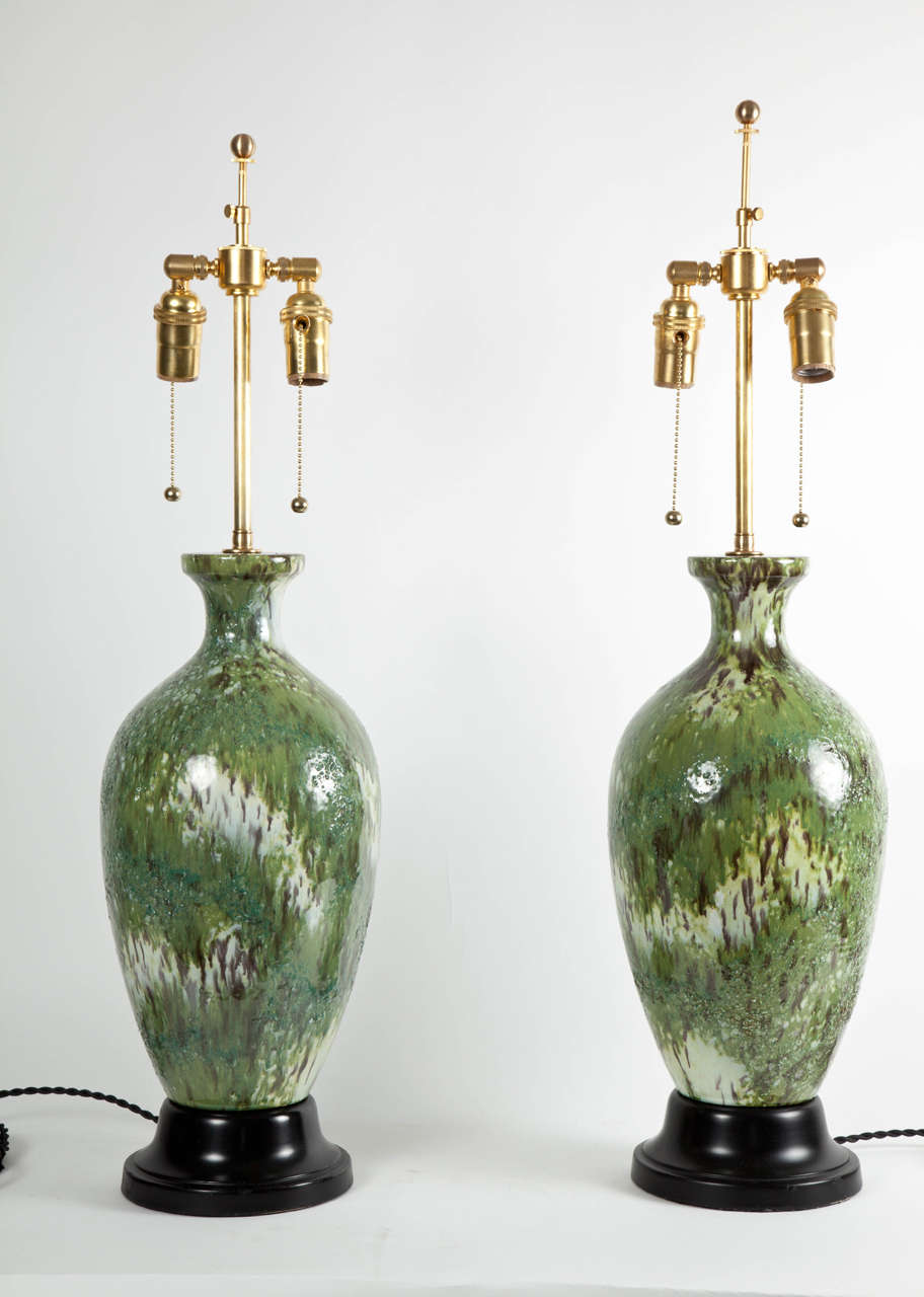 Variegated green drip glazes with a touch of volcanic texture over a white stoneware body with warm purplish manganese spots form the bodies of these mid-century Italian lamps. Unsigned but fabulous craftsmanship.  Newly mounted on satin-black