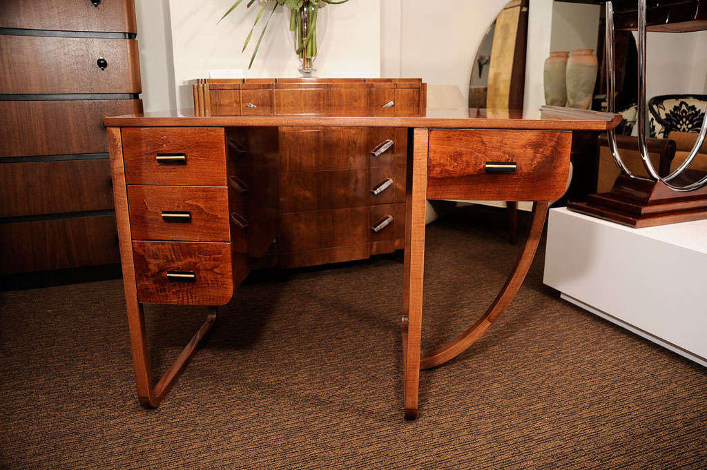 American Art Deco desk in the manor of Gilbert Rohde for Kohler with four drawers. Desk is maple stained mahogany. Handles are bakelite with brass trim.