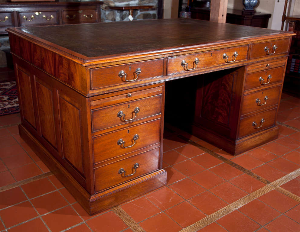 Featuring handsomely grained mahogany on raised side panels, this partners desk would make an attractive addition to any office. From its antiqued, hand tooled leather top to its four file drawers and slides, it combines form and function flawlessly.