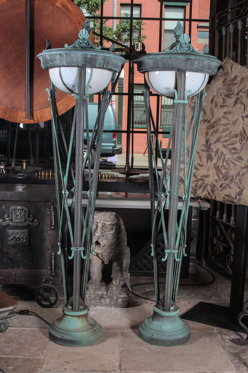 American, early 20th century, stunning grand pair of bronze entry lamps.  Glazed with panels of white curved glass with an excellent natural verdigris patina. Beautiful scroll details and a flame finial. Perfect as entry lamps or floor lamps in a