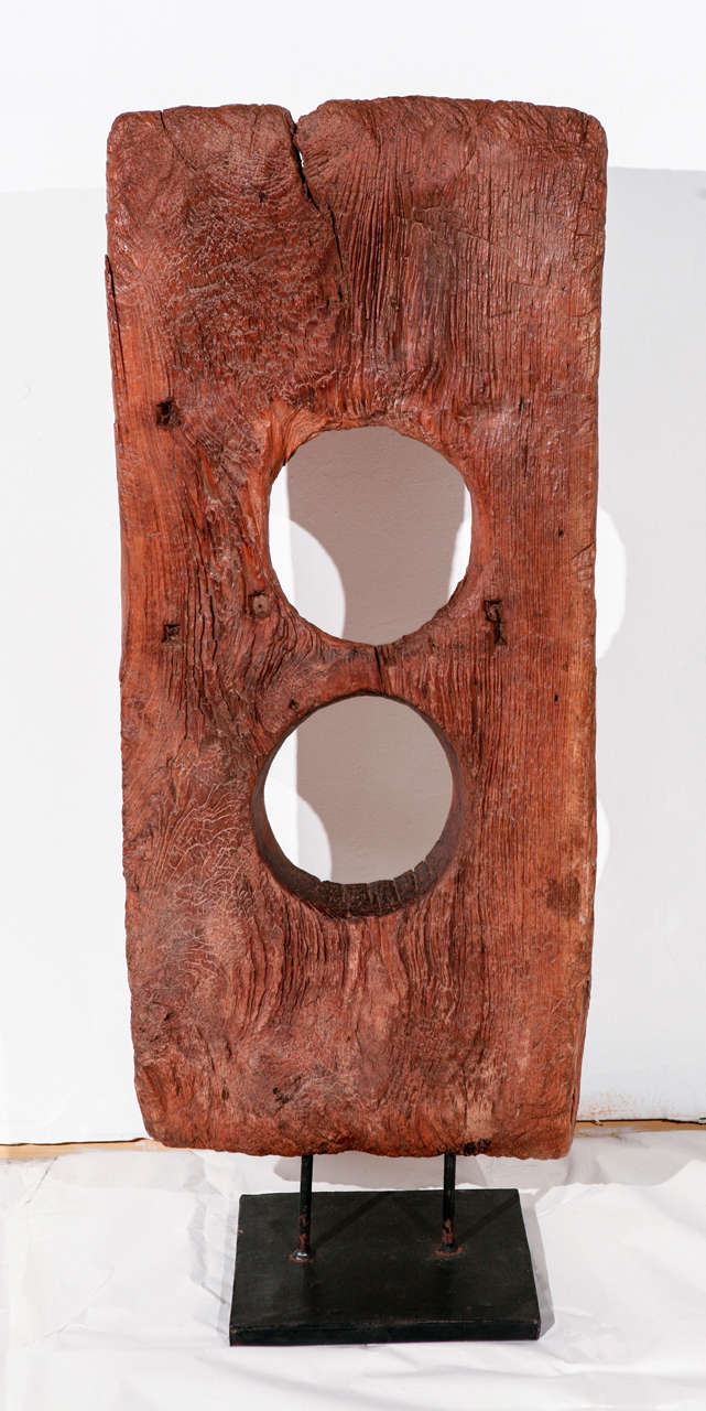 A vintage hand hewn abstract wood sculpture on an iron stand.