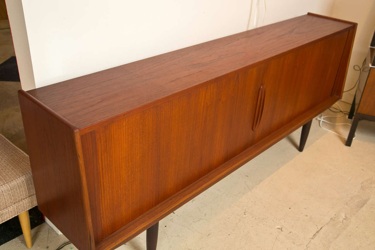 Sleek Mid-Century Modern teak credenza.  Tambour sliding doors, fitted interior with drawers and shelves.  Original finish in excellent condition,