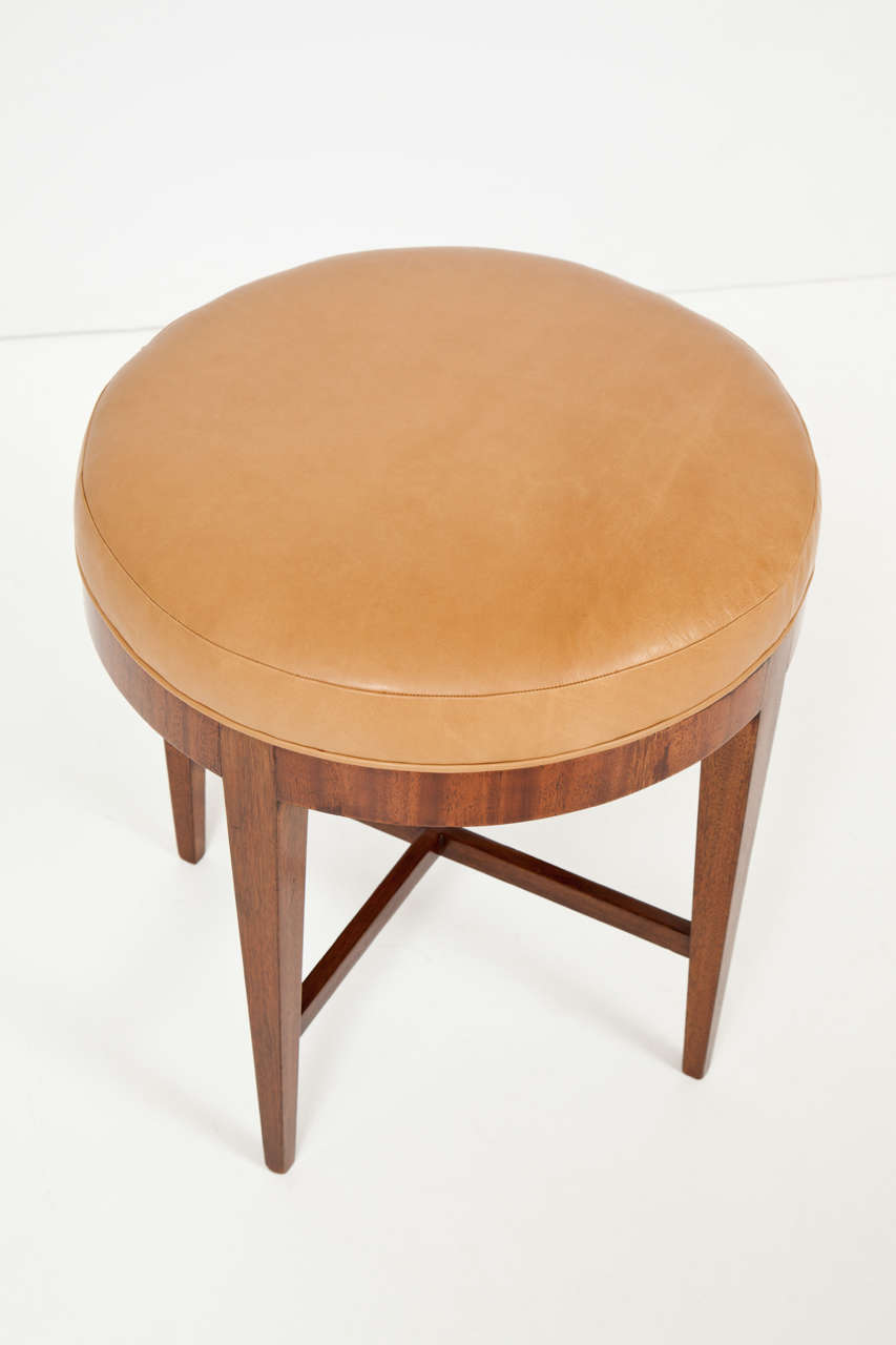 A Danish mahogany and leather stool attributed to Frits Henningsen, Circa 1940s, with a circular leather upholstered top raised on square tapered legs joined by a X-form stretcher.