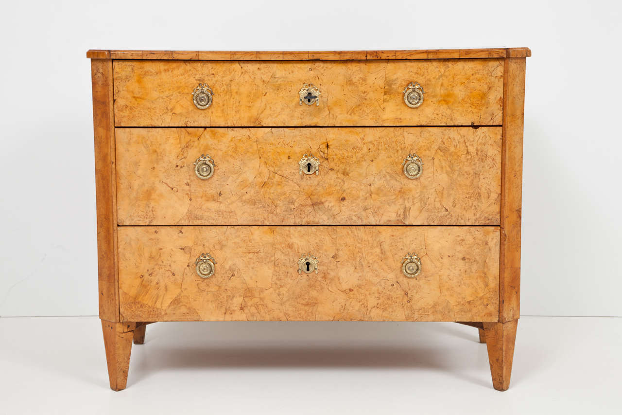 A good Swedish Late Gustavian alder root wood commode, early 19th century, the rectangular top with canted forcorners, above three long drawers flanked, canted sides raised on square tapered legs. Fitted with fire gilded escutcheons.