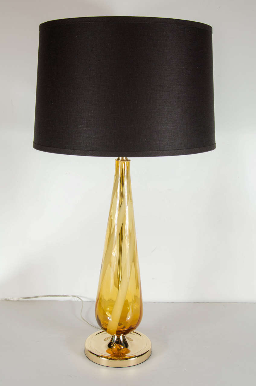 Mid-Century Modernist handblown Murano glass table lamp with an accentuated teardrop form featuring amber shaded Murano glass swirled with vertical stripes of white milk glass. It has brass fittings and large brass stand with concave and stepped