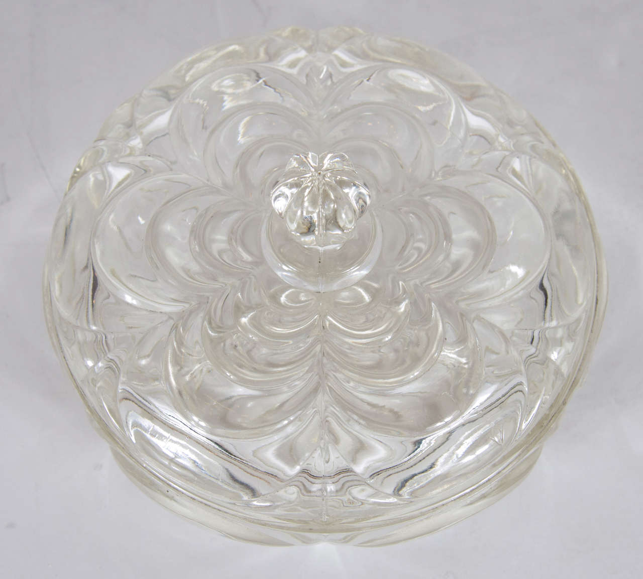 Art Deco glass dish with three inside divided compartments and a matching glass lid that features a fluted raised handle as a centerpiece that showcases a multilayered, scalloped floral design that is mimicked on the dish bottom.  It would be a