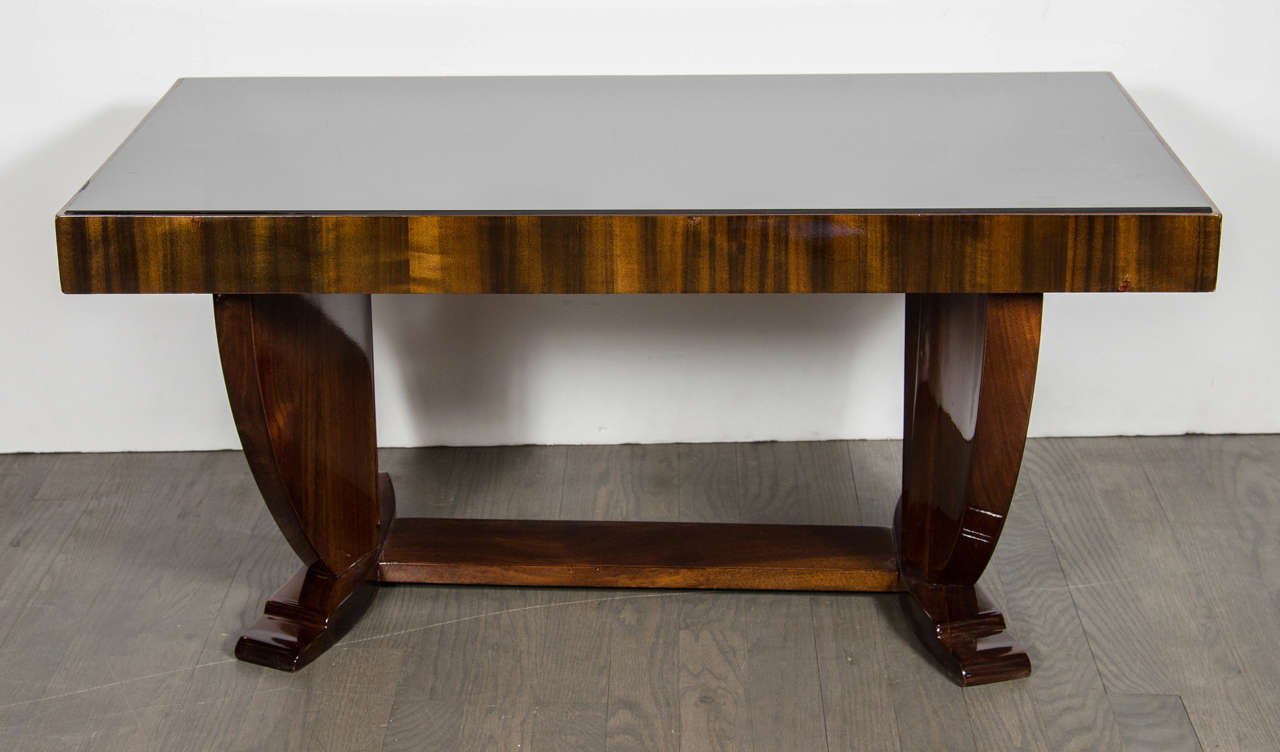 Art Deco Skyscraper style cocktail table in book-matched Walnut with a vitrolite top that has a book-matched banded Walnut surround that sits atop support legs with curved, skyscraper design and arched, stepped feet.  The support legs sit at a