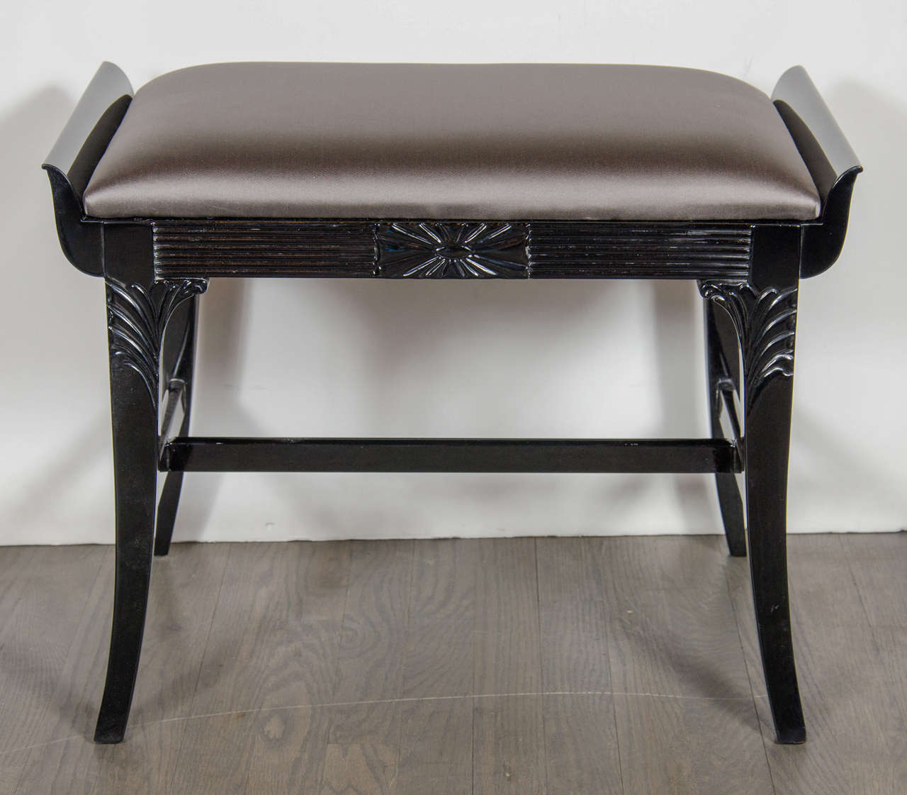 1940's Hollywood hand-carved bench / stool by Grosfeld House in ebonized Walnut featuring sloped design arms that extend up from the fluted surround featuring a sunburst design centerpiece.  The legs have a slight splayed design topped with stylized
