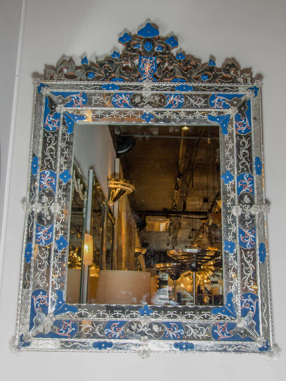 Exquisite Venetian style mirror with inset Royal Blue appliqués, some with hand-painted flourishes, that surround the mirror and embellish the crown.  This mirror supports a stunning crown centerpiece with multiply borders of reversed etched and