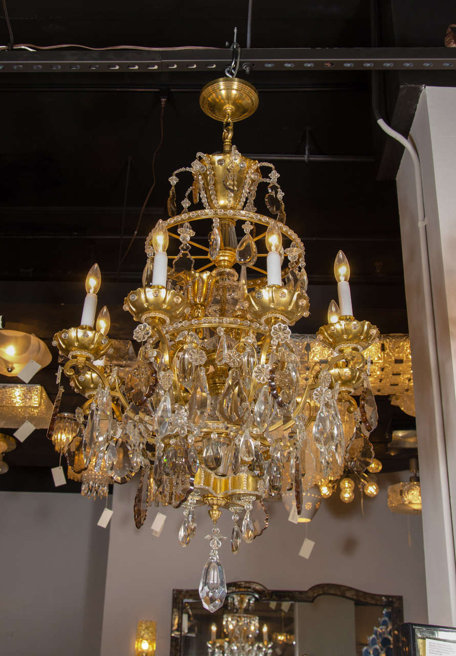This stunning eight arm 19th Century Louis XVI style gilt bronze chandelier is generously adorned with sophisticated clear and smoked fine cut crested crystals, beaded chain crystals, multi faceted drop crystals and crystal florets. It has recessed