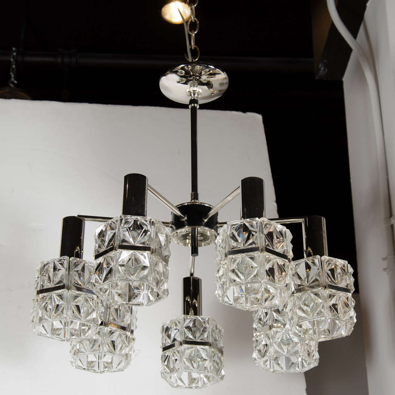 Mid-Century Modernist chandelier by Kinkelday. This chandelier features seven downward hanging shades that each consist of faceted crystal squares with a hand-cut diamond pattern. Each shade contains of two rows of faceted crystal squares that are